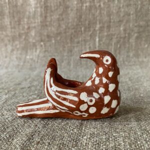 Emma Carlow pottery whistle in the shape of a bird on a cloth background