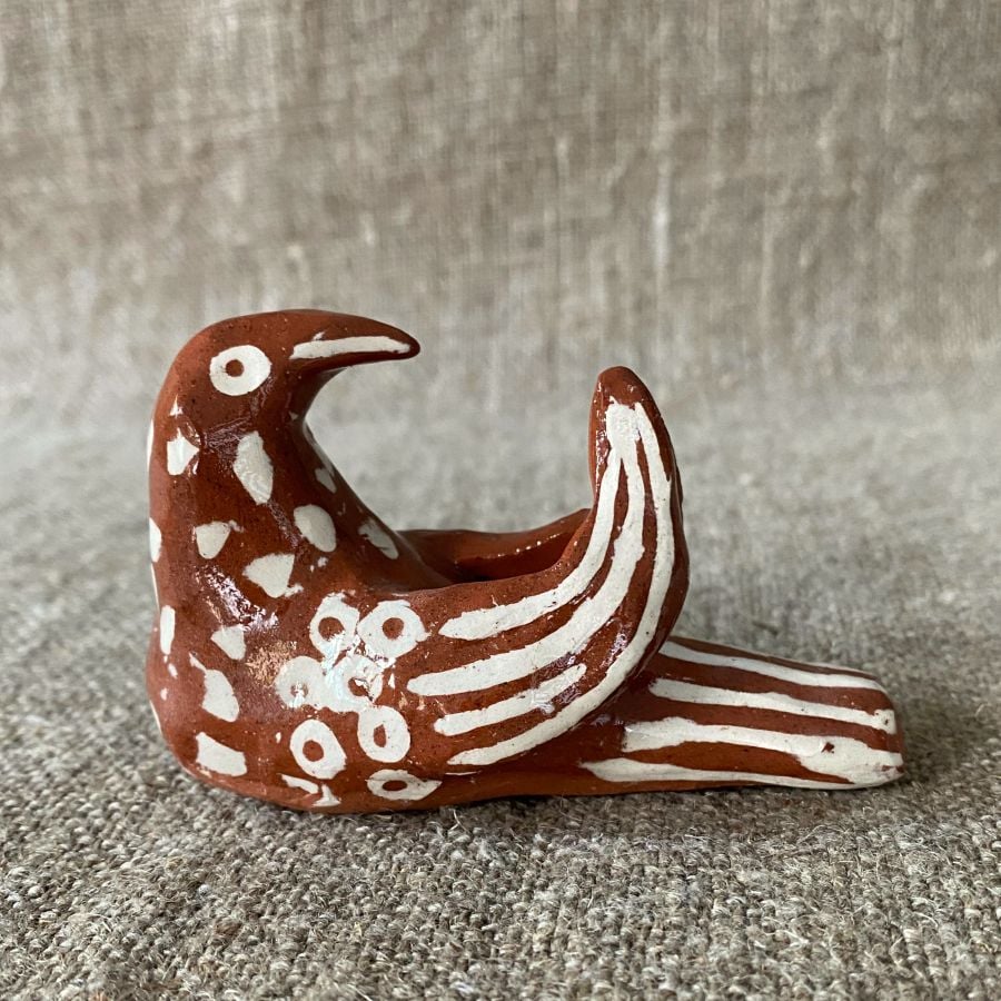 Emma Carlow pottery whistle in the shape of a bird on a cloth background