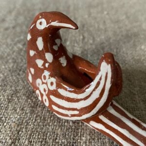 Emma Carlow pottery whistle in the shape of a bird on a cloth background