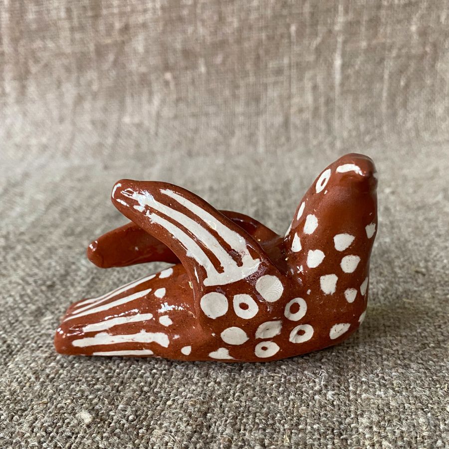 Emma Carlow pottery whistle in the shape of a bird on a cloth background