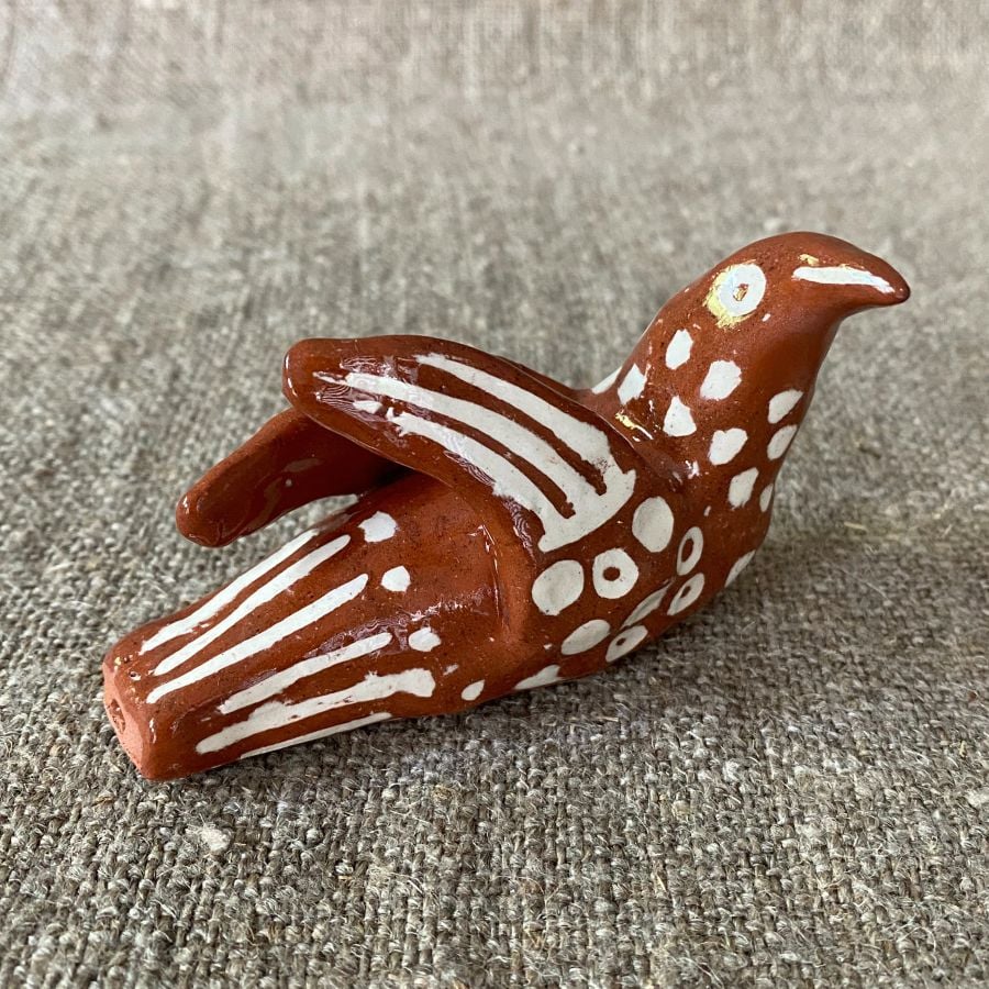 Emma Carlow pottery whistle in the shape of a bird on a cloth background