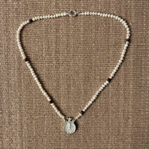 A seed pearl and red tigers eye necklace with a cast silver pomegranate pendant. Clare de la Torre.