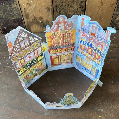 Emily Sutton's illustrated High Street advent calendar, upright against a wooden backdrop