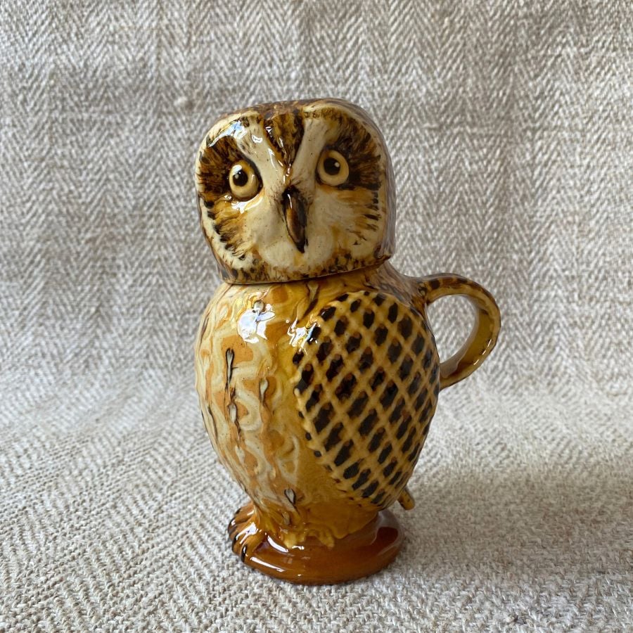 Ceramic slipware owl jug against a pale fabric background
