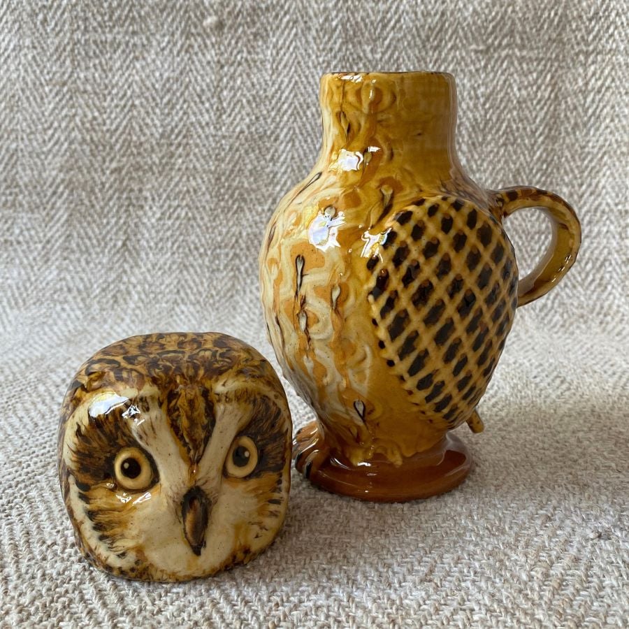 Ceramic slipware owl jug against a pale fabric background
