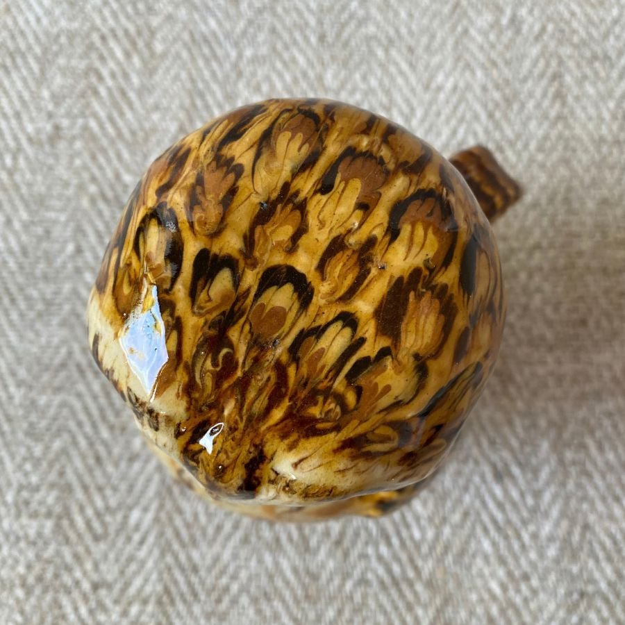 Ceramic slipware owl jug against a pale fabric background