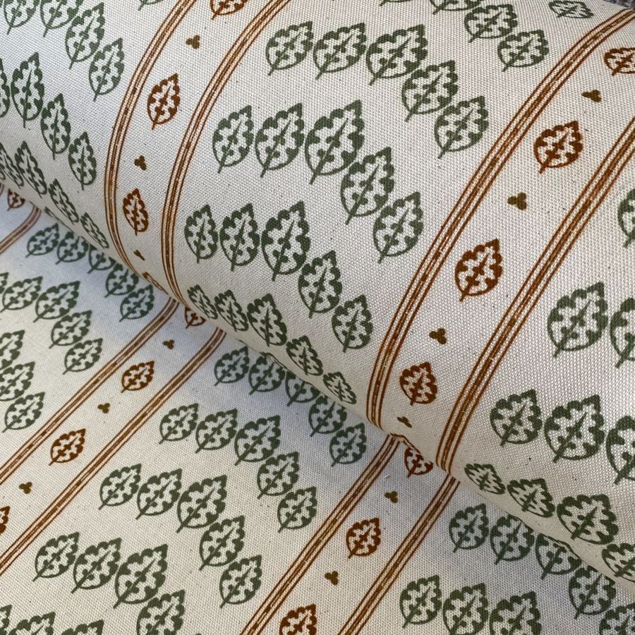 Striped pattern fabric on a slant with a repeated tree design in green & brown