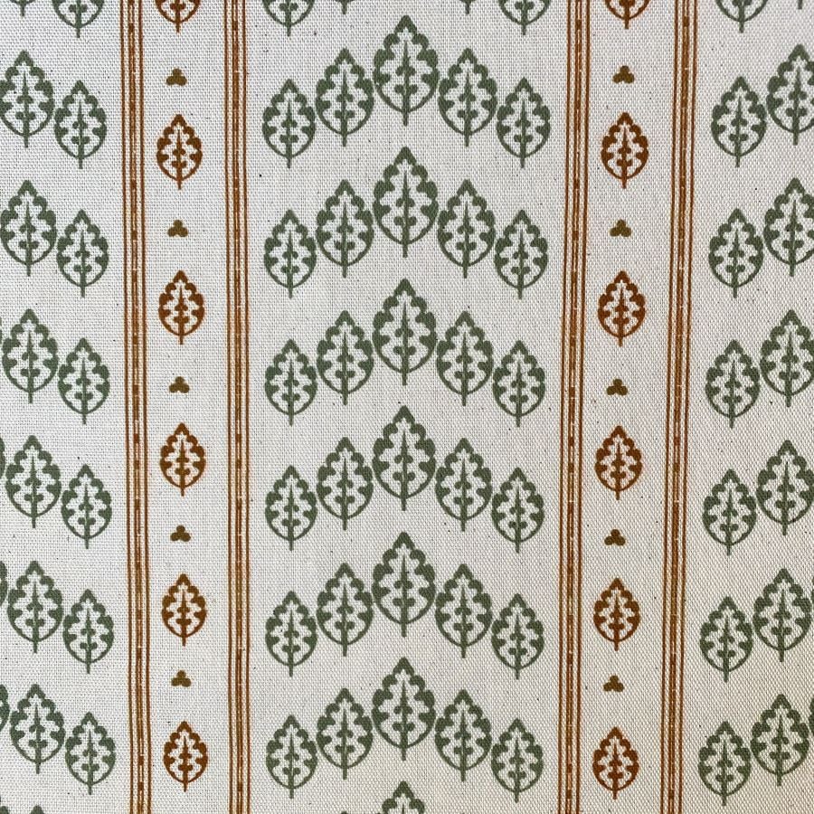 Striped pattern fabric on a slant with a repeated tree design in green & brown