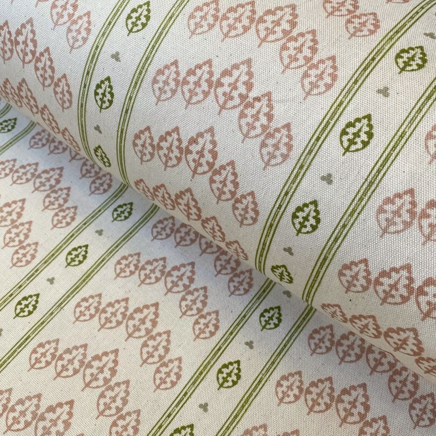 Detail of a roll of striped fabric with a tree motif, in pink, green & ivory