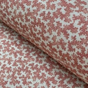Slanted roll of fabric featuring a small scale coral design in pinkish red
