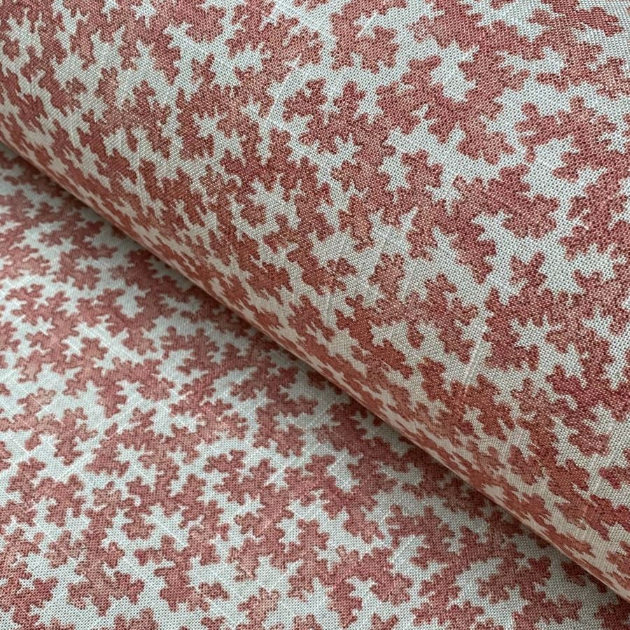 Slanted roll of fabric featuring a small scale coral design in pinkish red