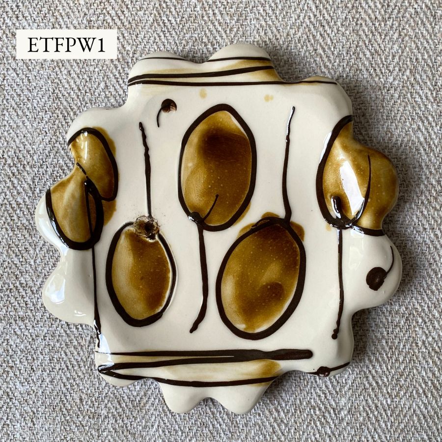 White glazed plate with scalloped edge againsta a pale fabric background
