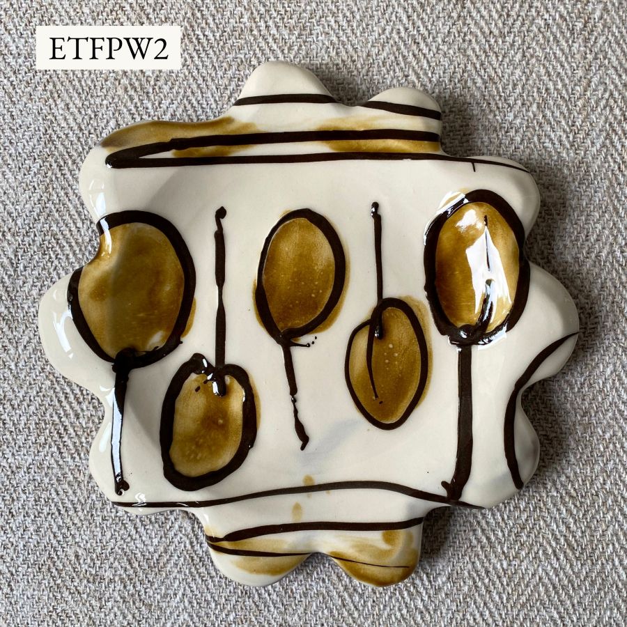 White glazed plate with scalloped edge againsta a pale fabric background