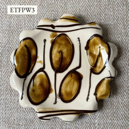 White glazed plate with scalloped edge againsta a pale fabric background