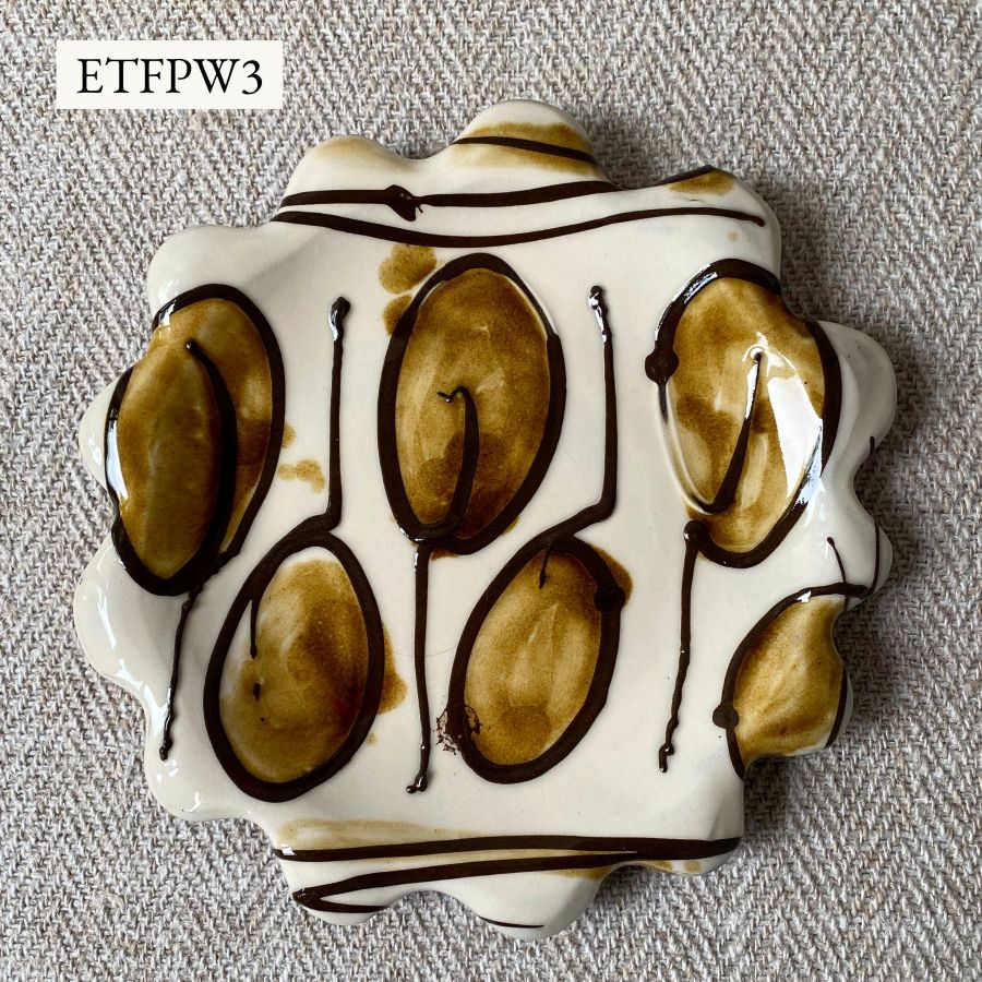 White glazed plate with scalloped edge againsta a pale fabric background