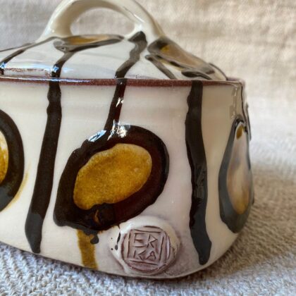 White glazed butter dish with lid against a fabric background