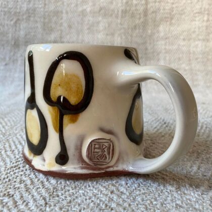 White slipware mug against a white fabric background
