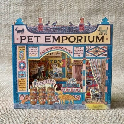 A 3D stand up card of a pet shop illustrated by Emily Sutton against a pale fabric background