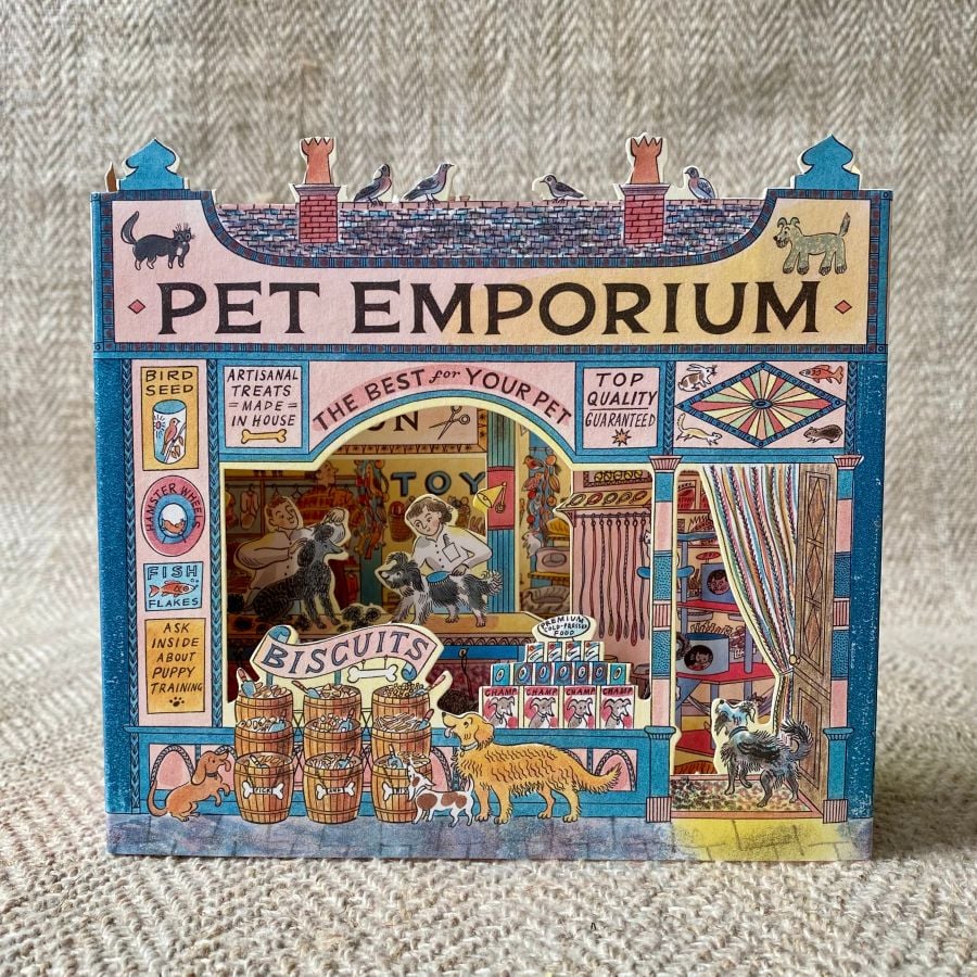 A 3D stand up card of a pet shop illustrated by Emily Sutton against a pale fabric background