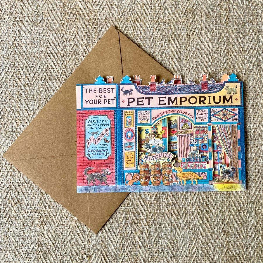 A 3D stand up card of a pet shop illustrated by Emily Sutton against a pale fabric background
