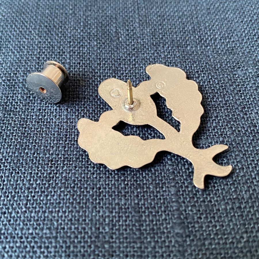 Pewter brooch in the shape of an acorn & leaves against a blue fabric background