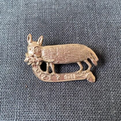 Pewter brooch in the shape of a hand against a blue fabric background