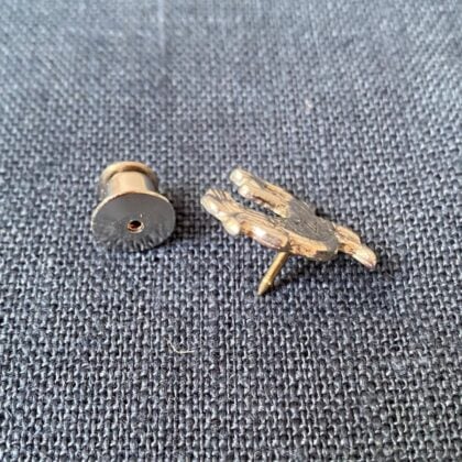 Pewter brooch in the shape of a cockerel against a blue fabric background