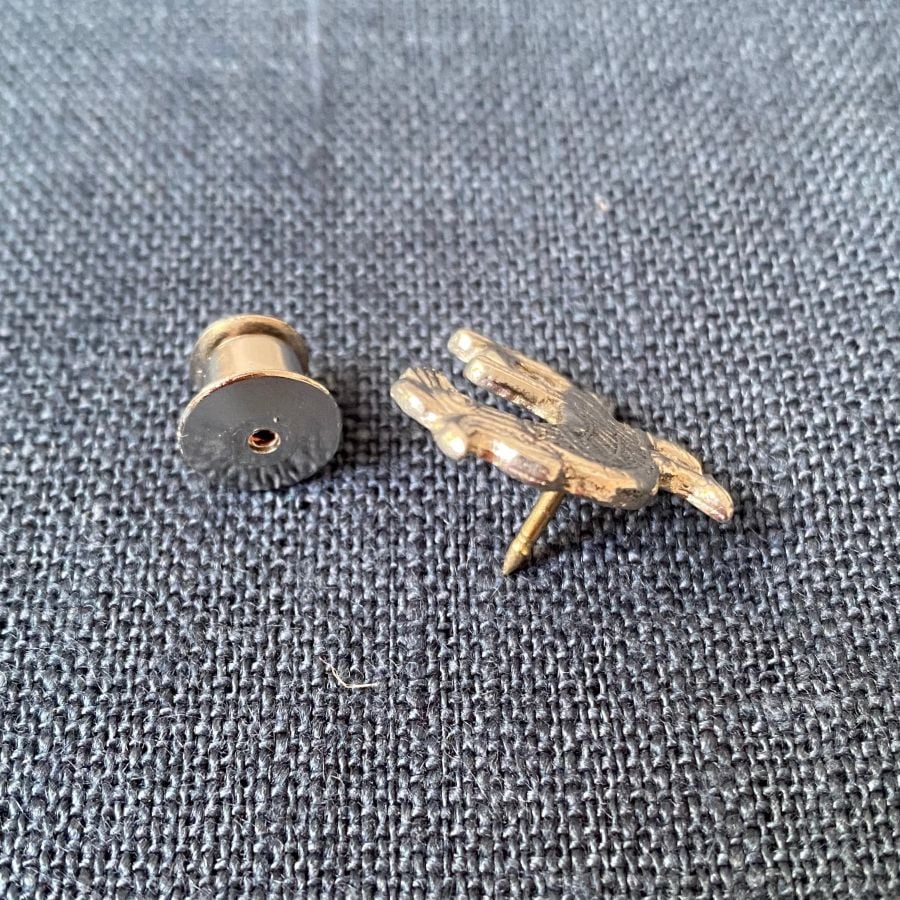 Pewter brooch in the shape of a cockerel against a blue fabric background