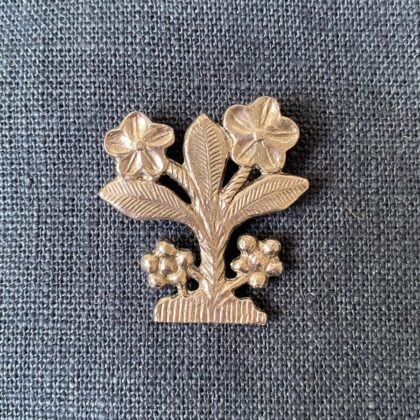 Pewter brooch in the shape of an owl against a blue fabric background