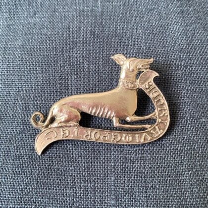 Pewter brooch in the shape of a greyhound against a blue fabric backgroun