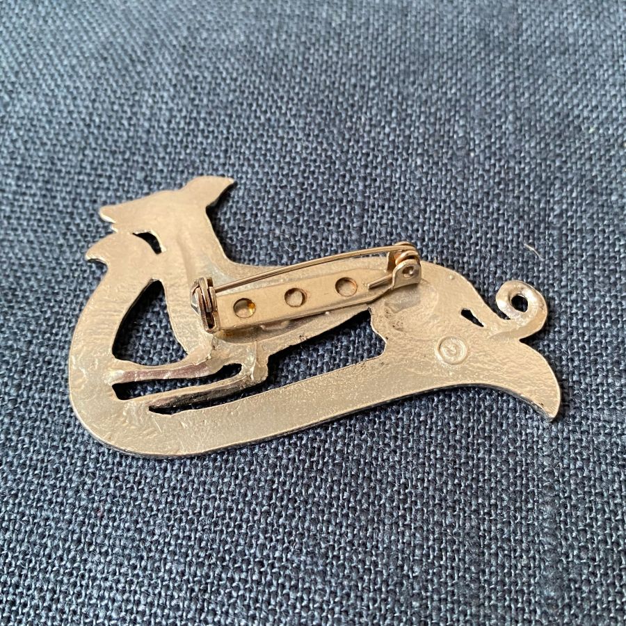 Pewter brooch in the shape of a greyhound against a blue fabric background