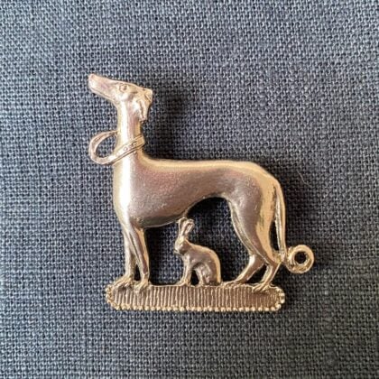 Pewter brooch in the shape of a dog and hare against a blue fabric backgroun