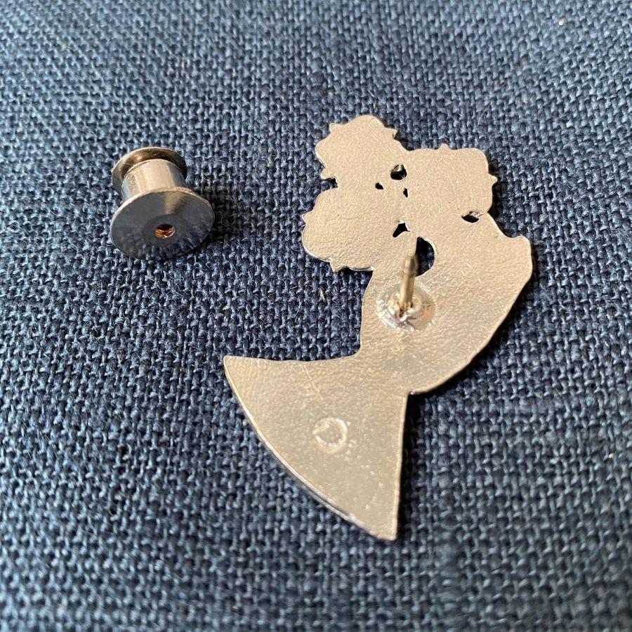 Pewter brooch in the shape of a hand against a blue fabric background