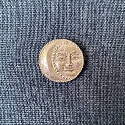 Pewter brooch in the shape of a FULL MOON against a blue fabric backgroun