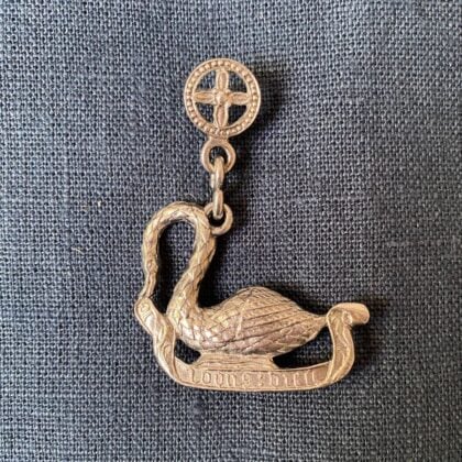 Pewter brooch in the shape of an arch-necked swan against a blue fabric backgroun