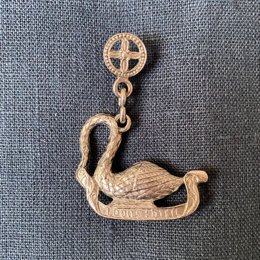 Pewter brooch in the shape of an arch-necked swan against a blue fabric backgroun