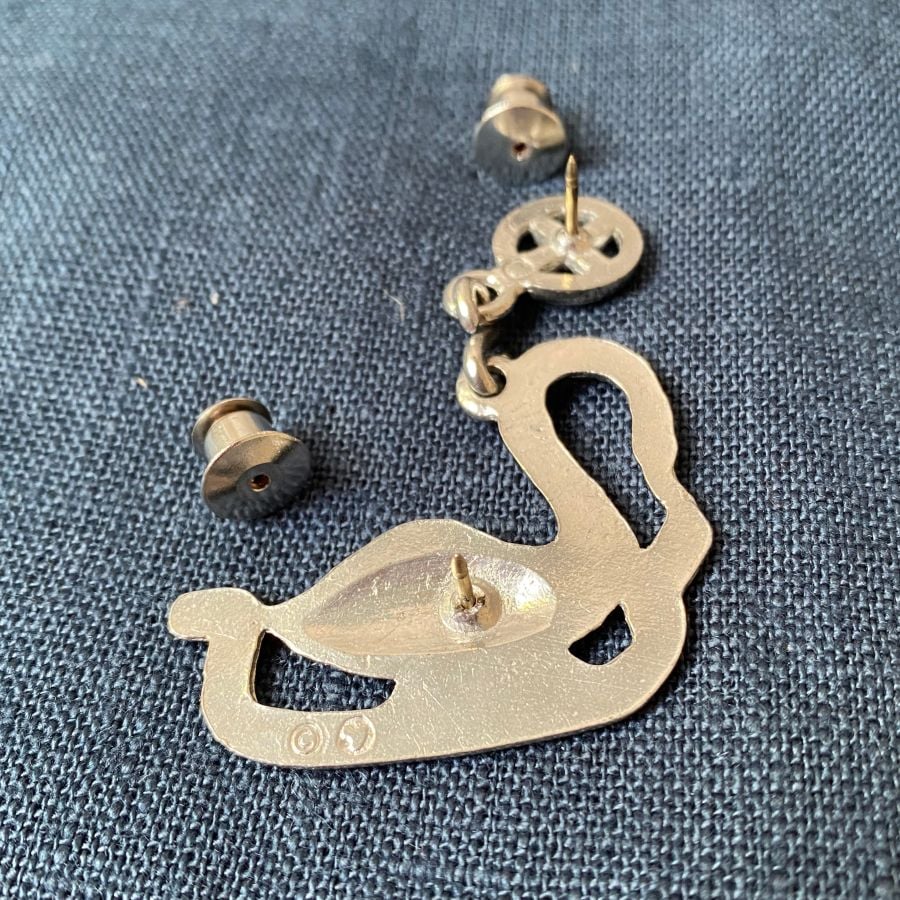 Pewter brooch in the shape of an arch-necked swan against a blue fabric background